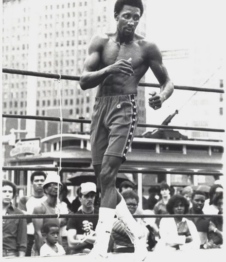 Boxer skipping rope before an outdoor crowd, black and white